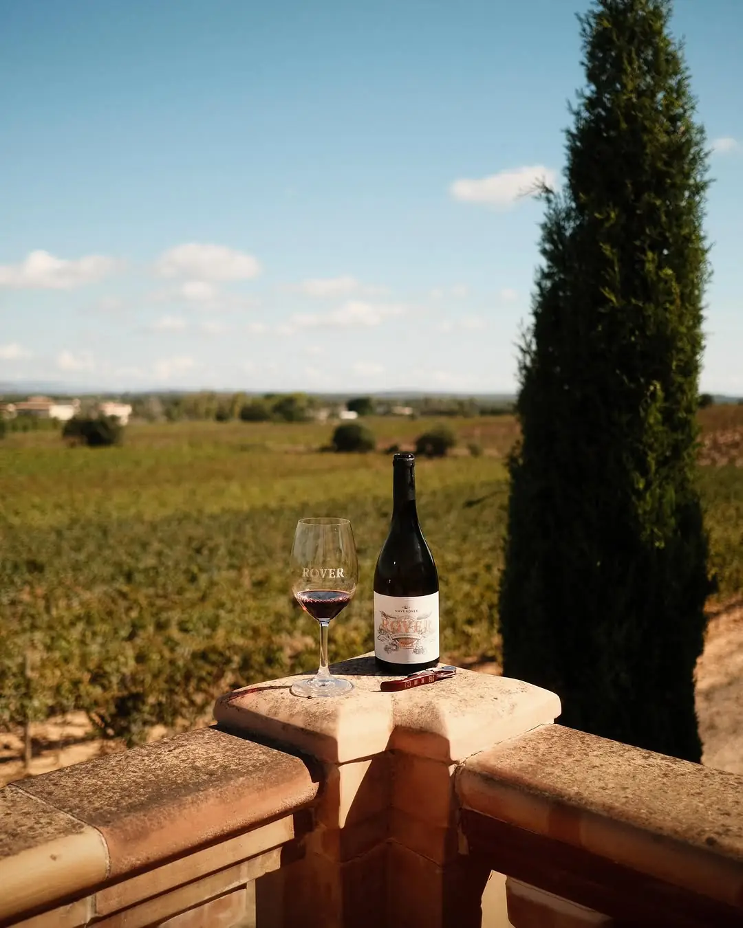 A glass and bottle of Naver Over wine on a terrace above the vines