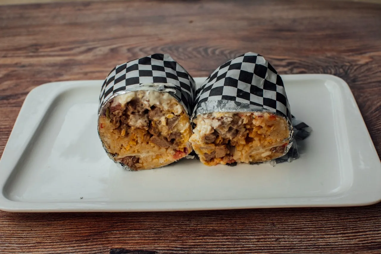 Two burritos wrapped in checkered paper on a plate