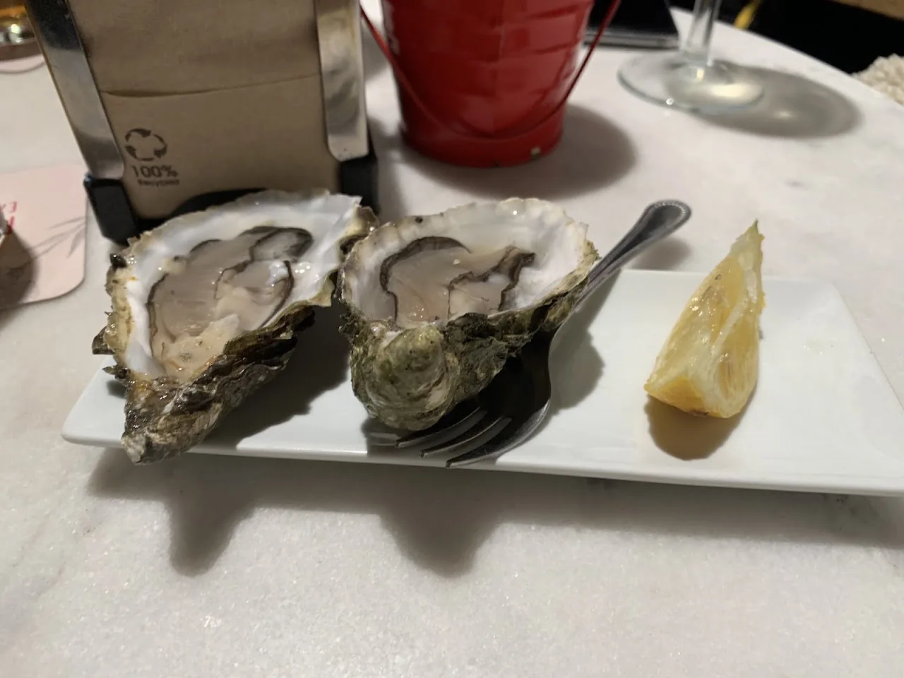 A plate of oysters on ice with a lemon wedge