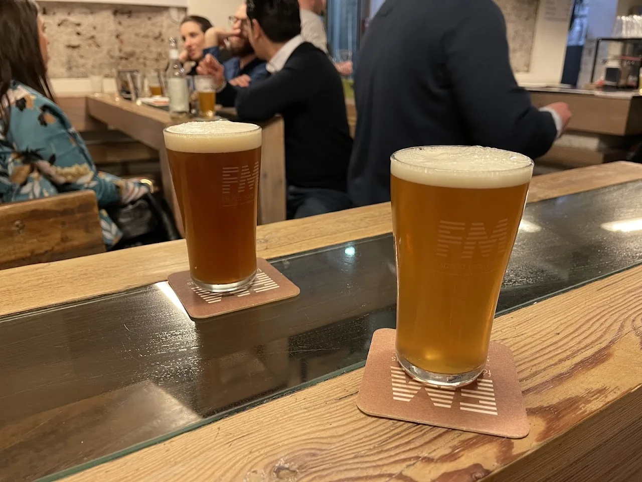 Two glasses of beer with foam heads on a bar counter