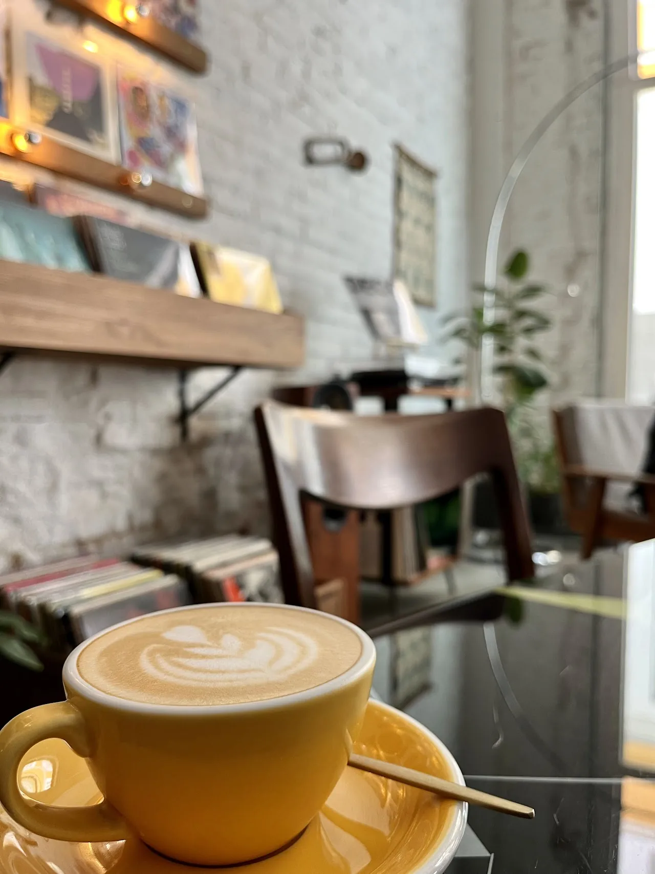 A latte in a yellow cup with rosette foam art on a marble table