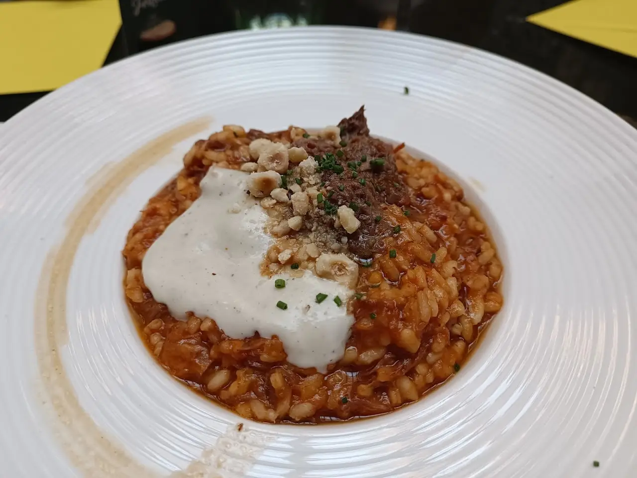 A stew topped with a creamy white cheese and crumbled nuts