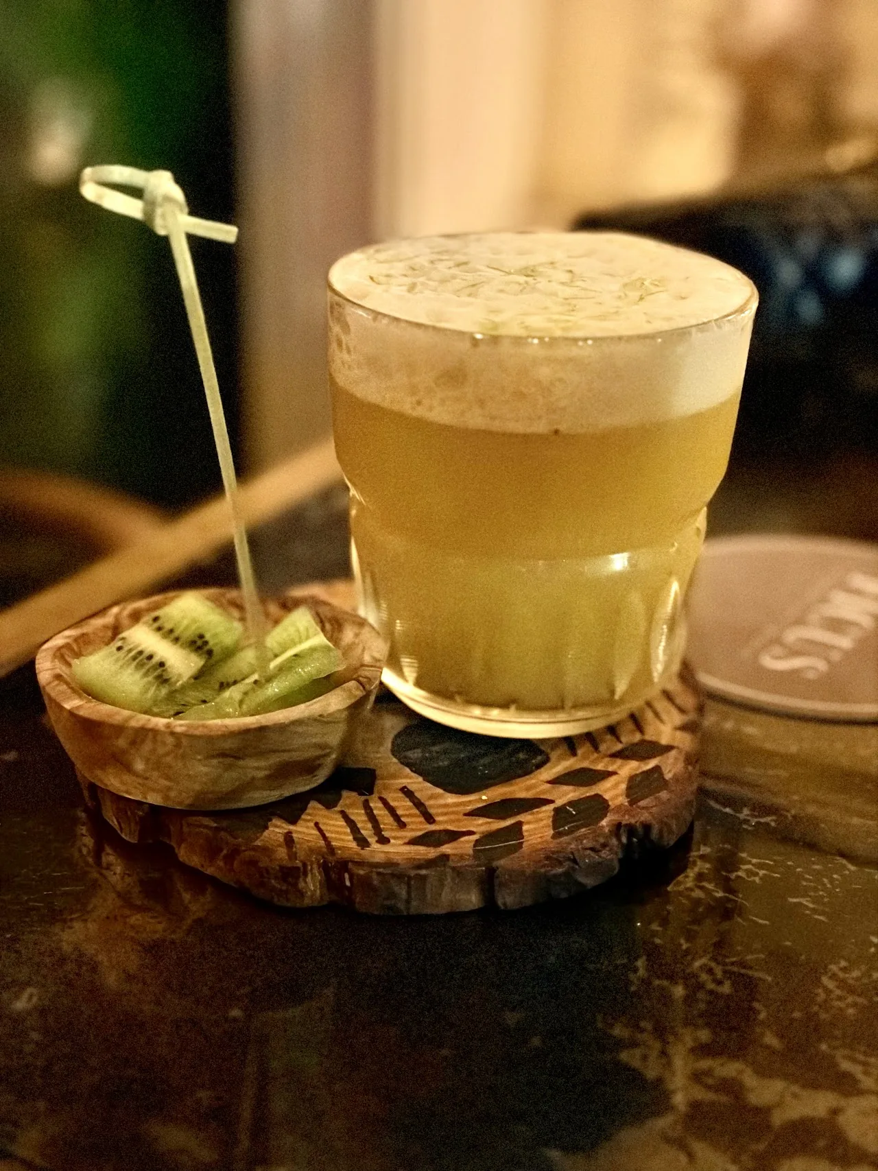 A frothy yellow cocktail served in a hollowed-out kiwi shell
