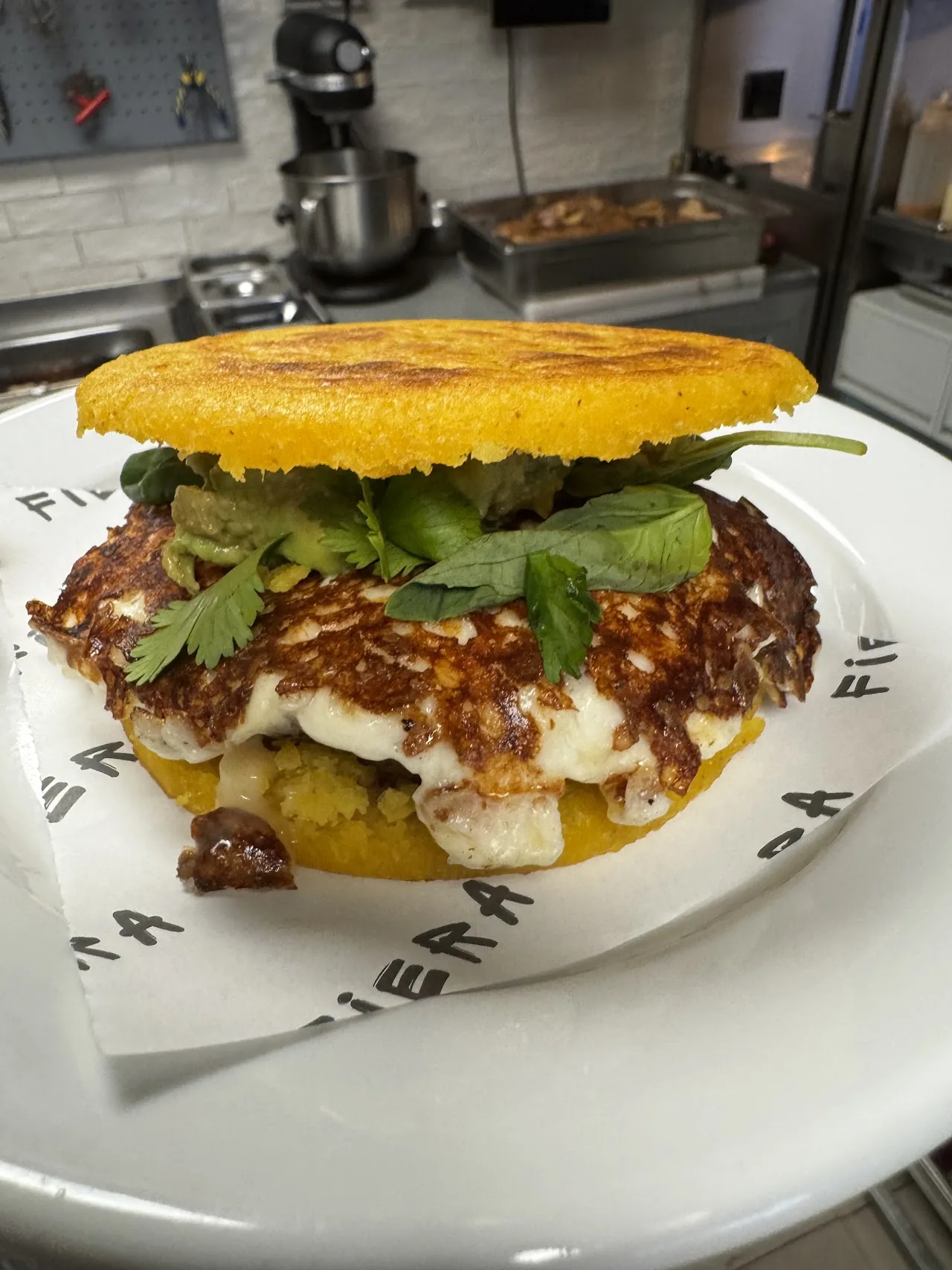 A stacked arepa sandwich with melted cheese and cilantro