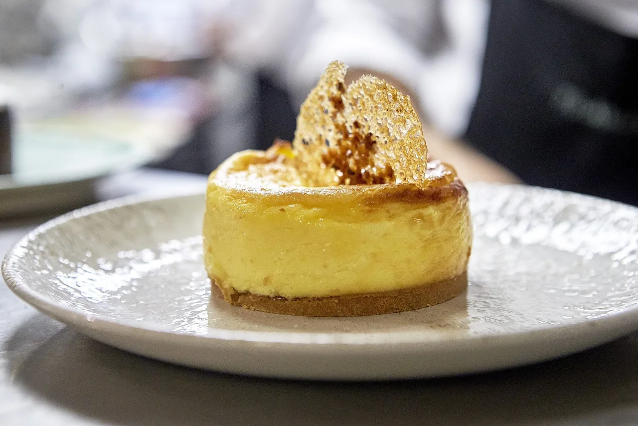 A round cheesecake topped with crumbs on a grey plate