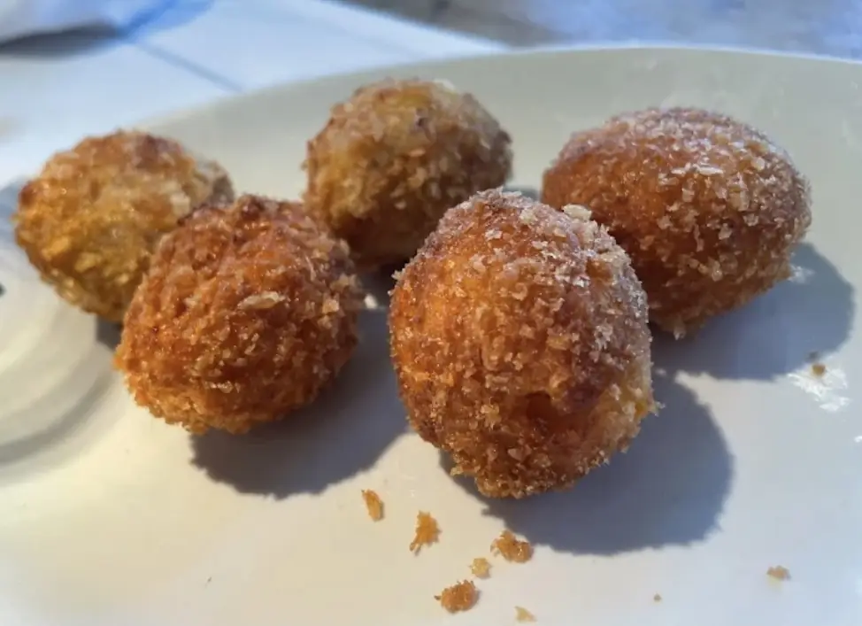 Five golden fried croquette balls on a white plate