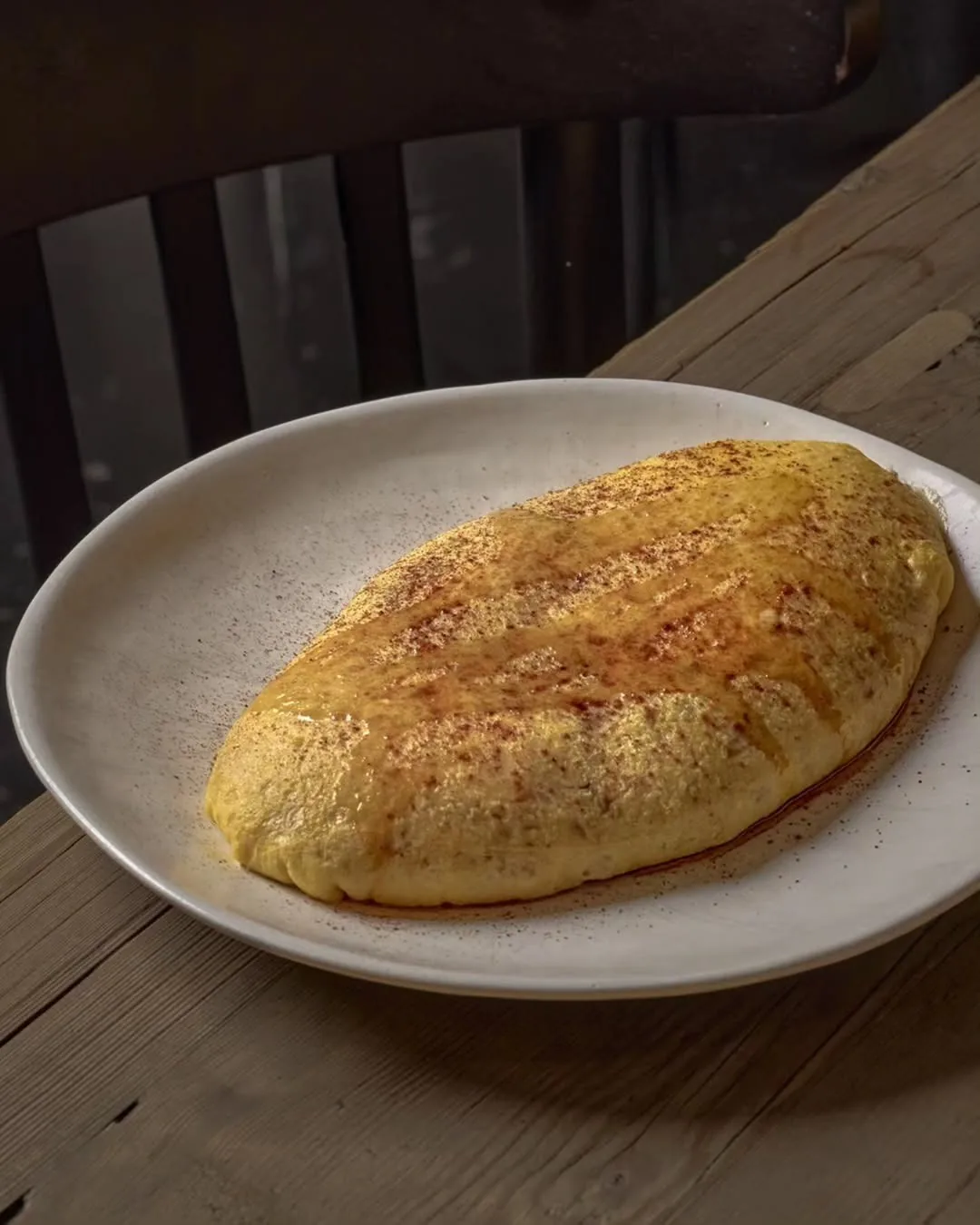 A golden folded omelette on a white plate on a wooden table