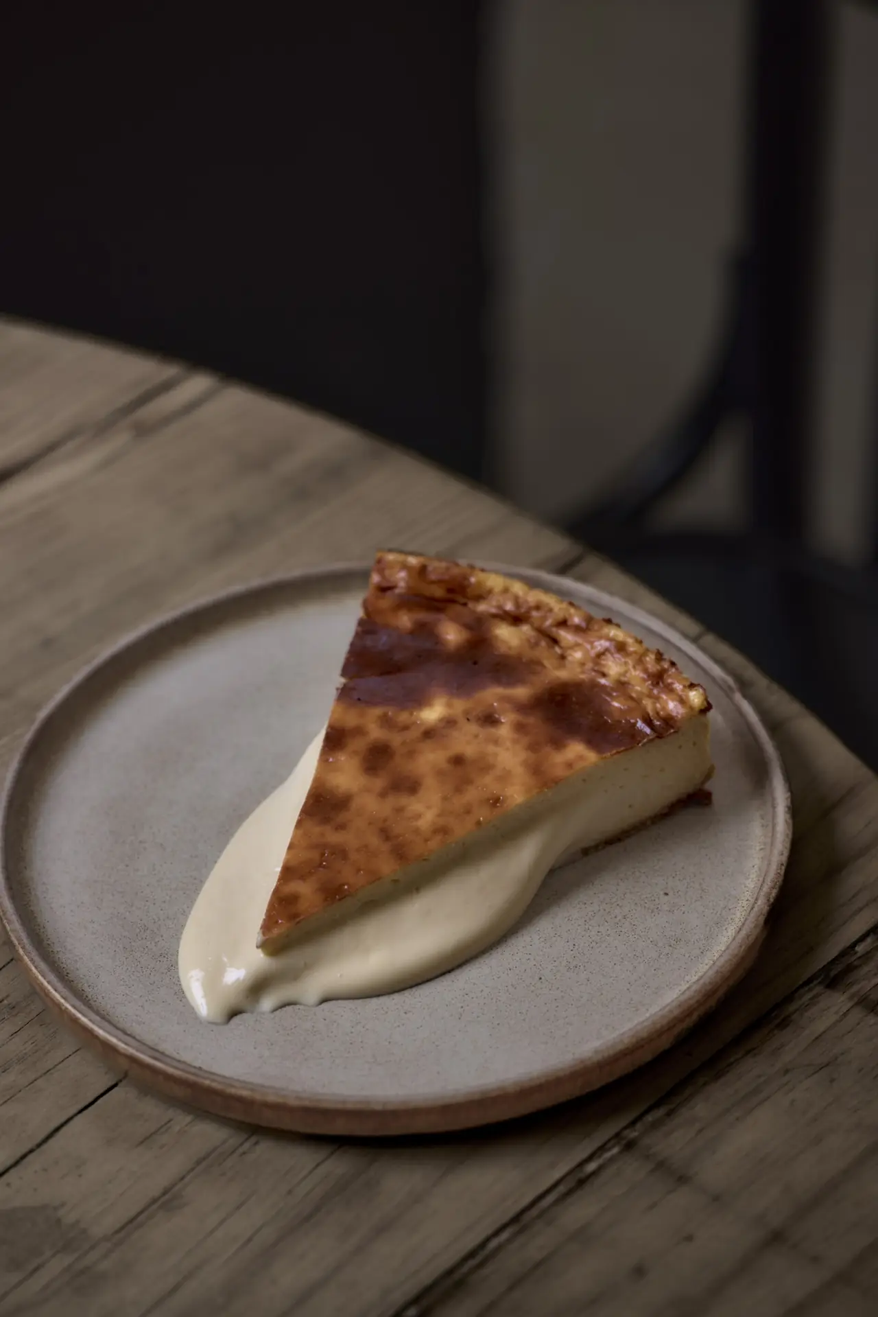 Slice of burnt Basque cheesecake on a stone plate with a swipe of cream sauce