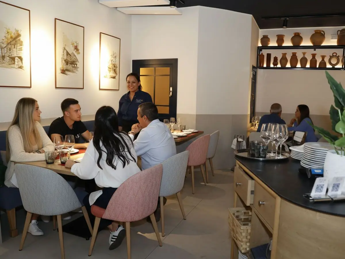 Dining room with guests seated at tables, watercolour prints on the wall, terracotta pot display and a wood service counter
