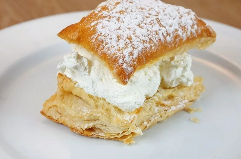 A puff pastry dessert filled with cream and dusted with icing sugar
