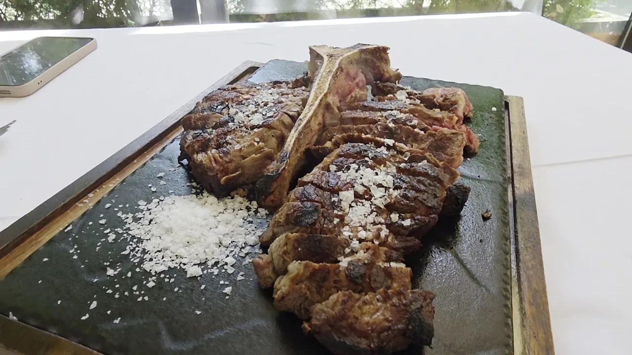 A tomahawk steak sliced and served on a wooden board