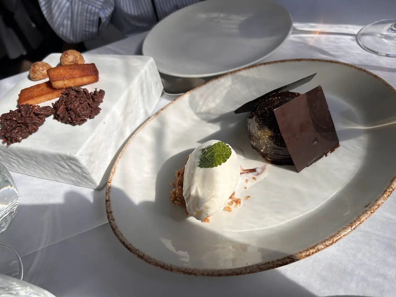 Chocolate dessert with dark chocolate tuile and a scoop of cream with mint, plus a side plate of petit fours