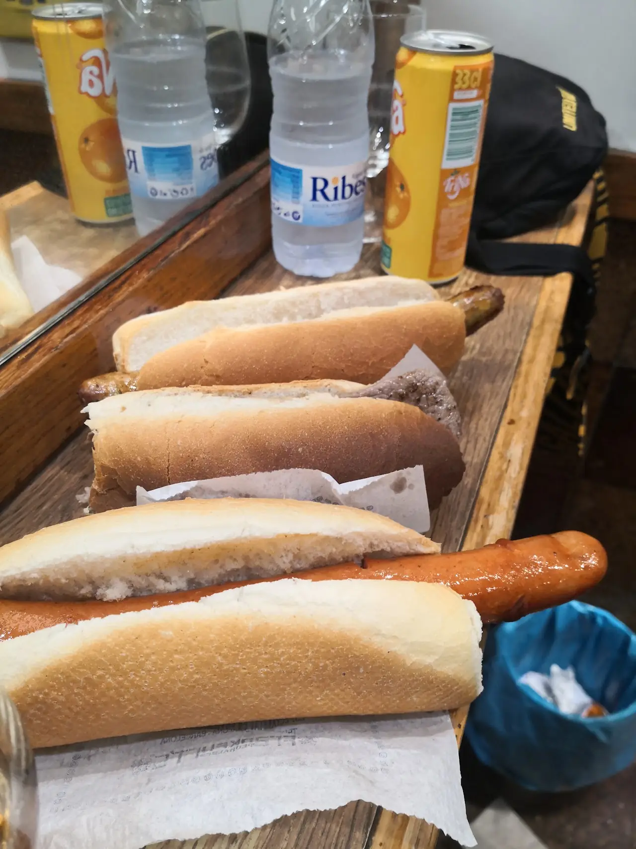 Row of hot dogs in bread rolls lined up on a wooden board, at Frankfurt Pedralbes.