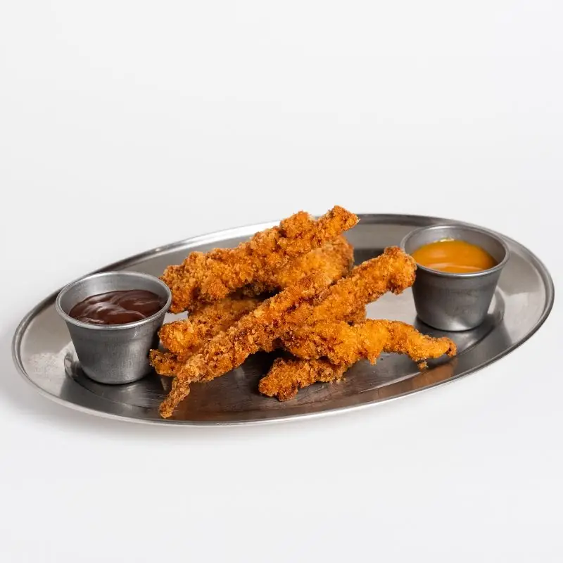 Breaded chicken tenders on a metal tray with two dipping sauces.