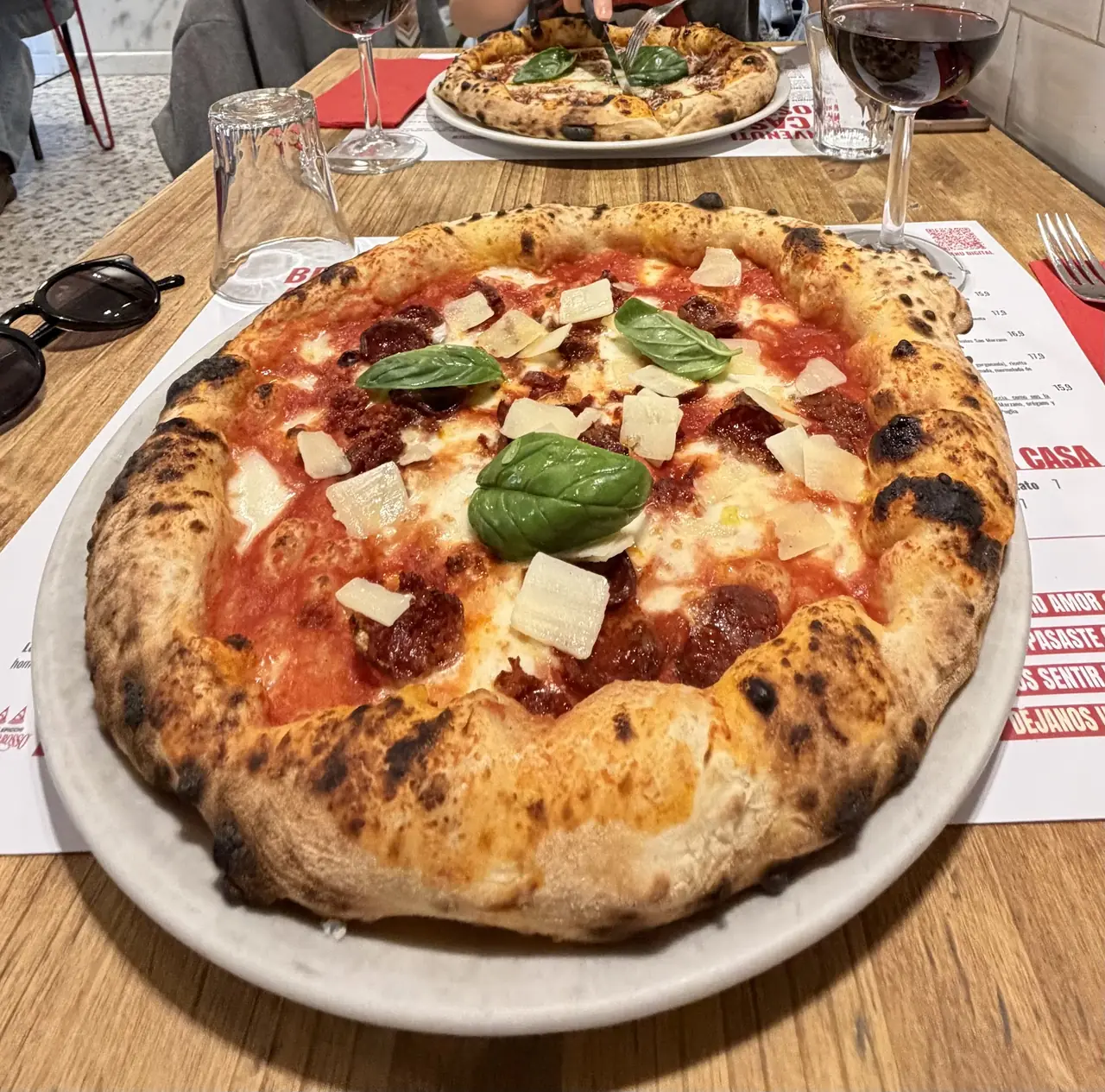 Neapolitan-style pizza with spicy salami, mozzarella, shaved cheese and fresh basil