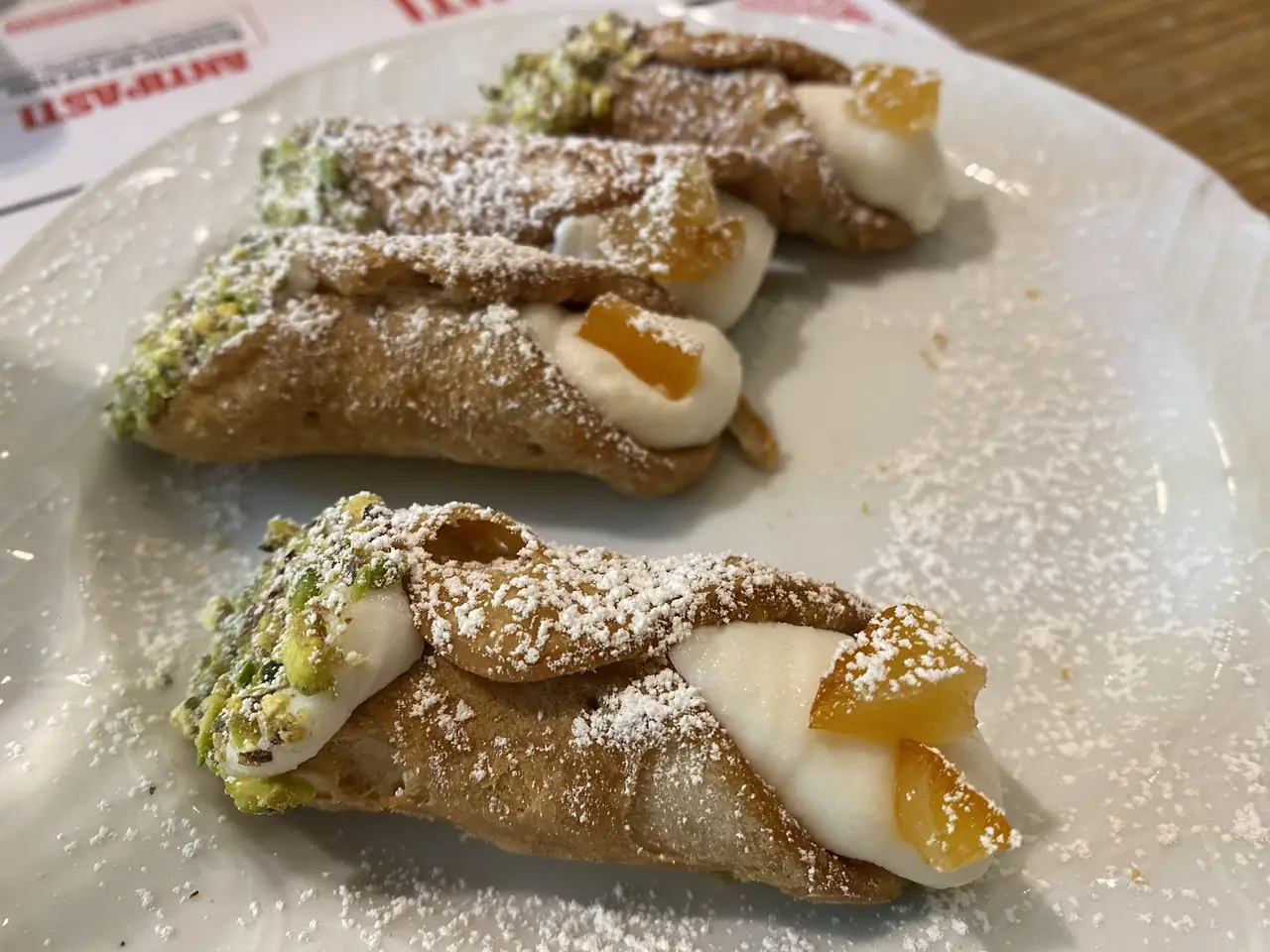 Cannoli with pistachio-crusted ends, ricotta filling and candied orange peel