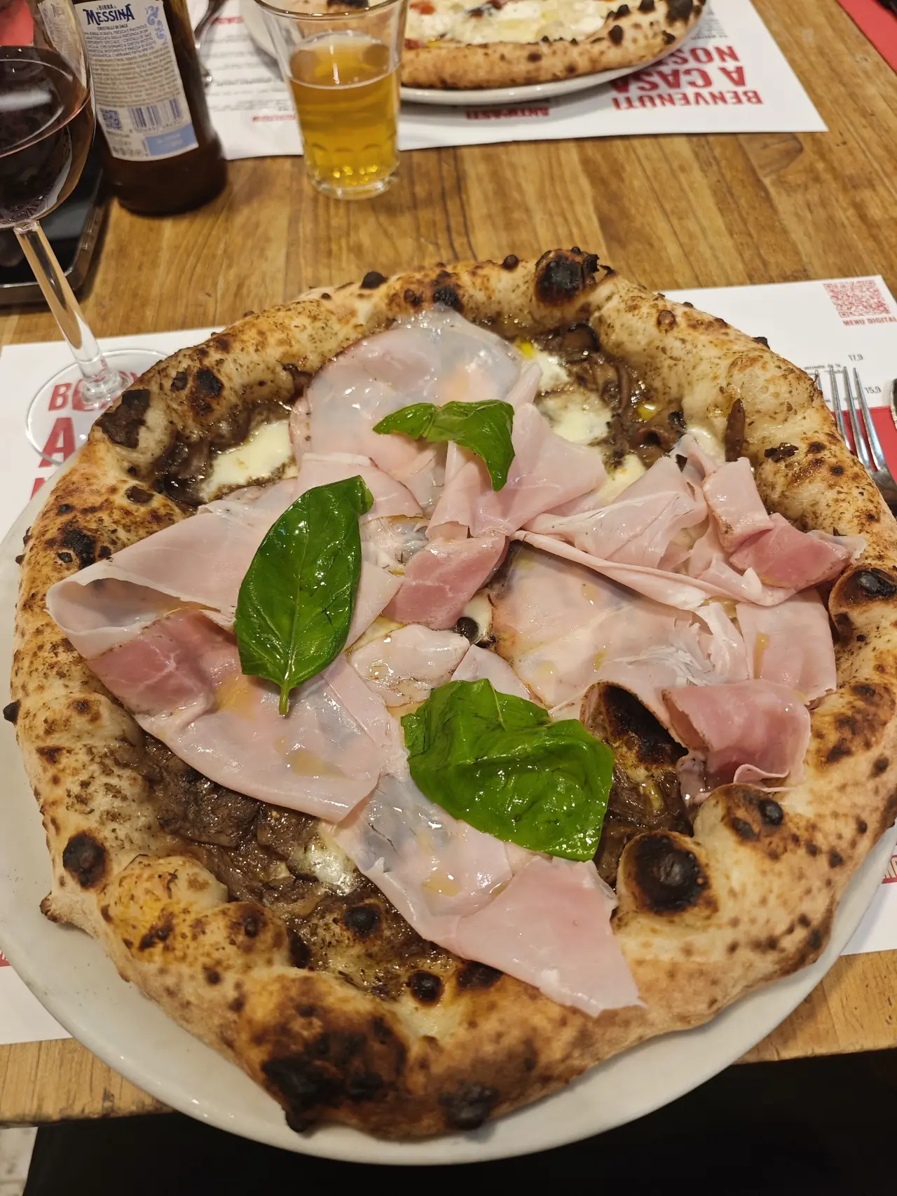 Neapolitan-style pizza topped with cooked ham, mushrooms and fresh basil