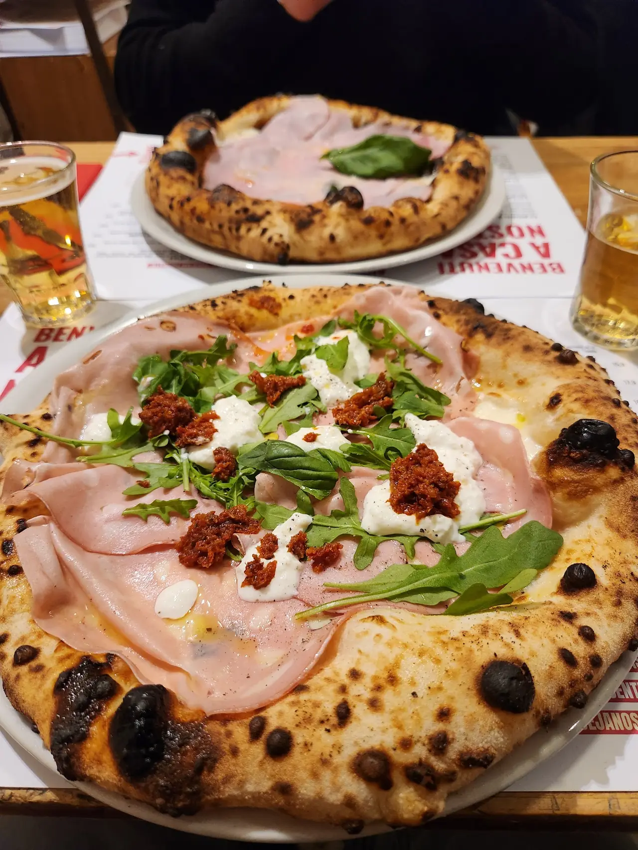 Neapolitan-style pizza with cooked ham, burrata, sun-dried tomato pesto and arugula