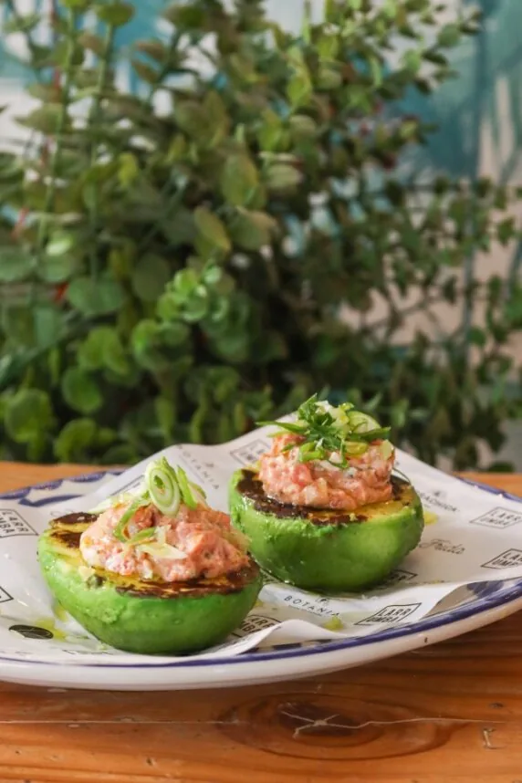 Two hollowed tomatoes filled with a pink seafood tartare