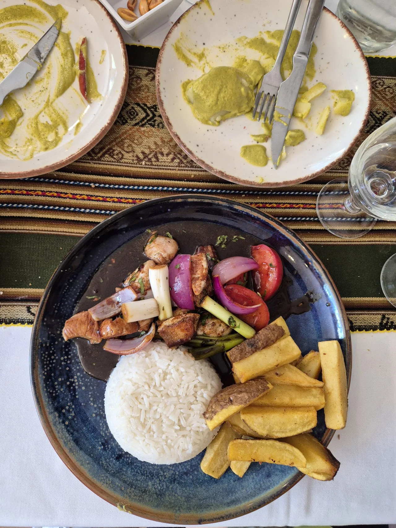 A plate of grilled meats, sausages, and fries with mustard dips