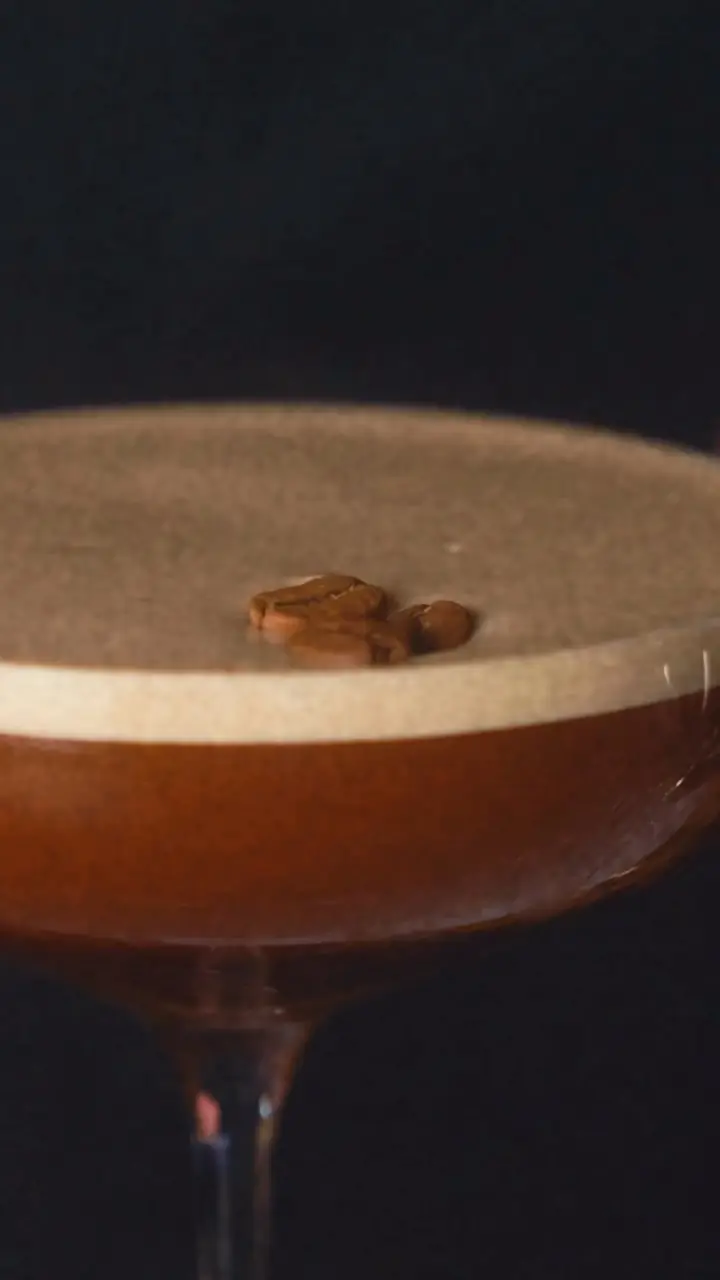 An espresso martini topped with coffee beans in a coupe glass.