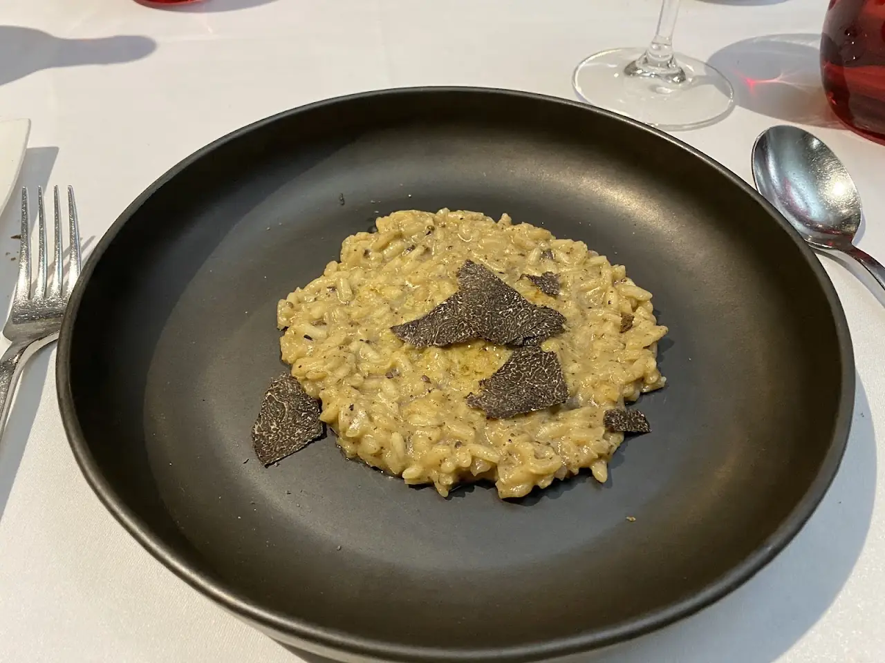 Creamy risotto topped with shaved black truffle on a dark plate.