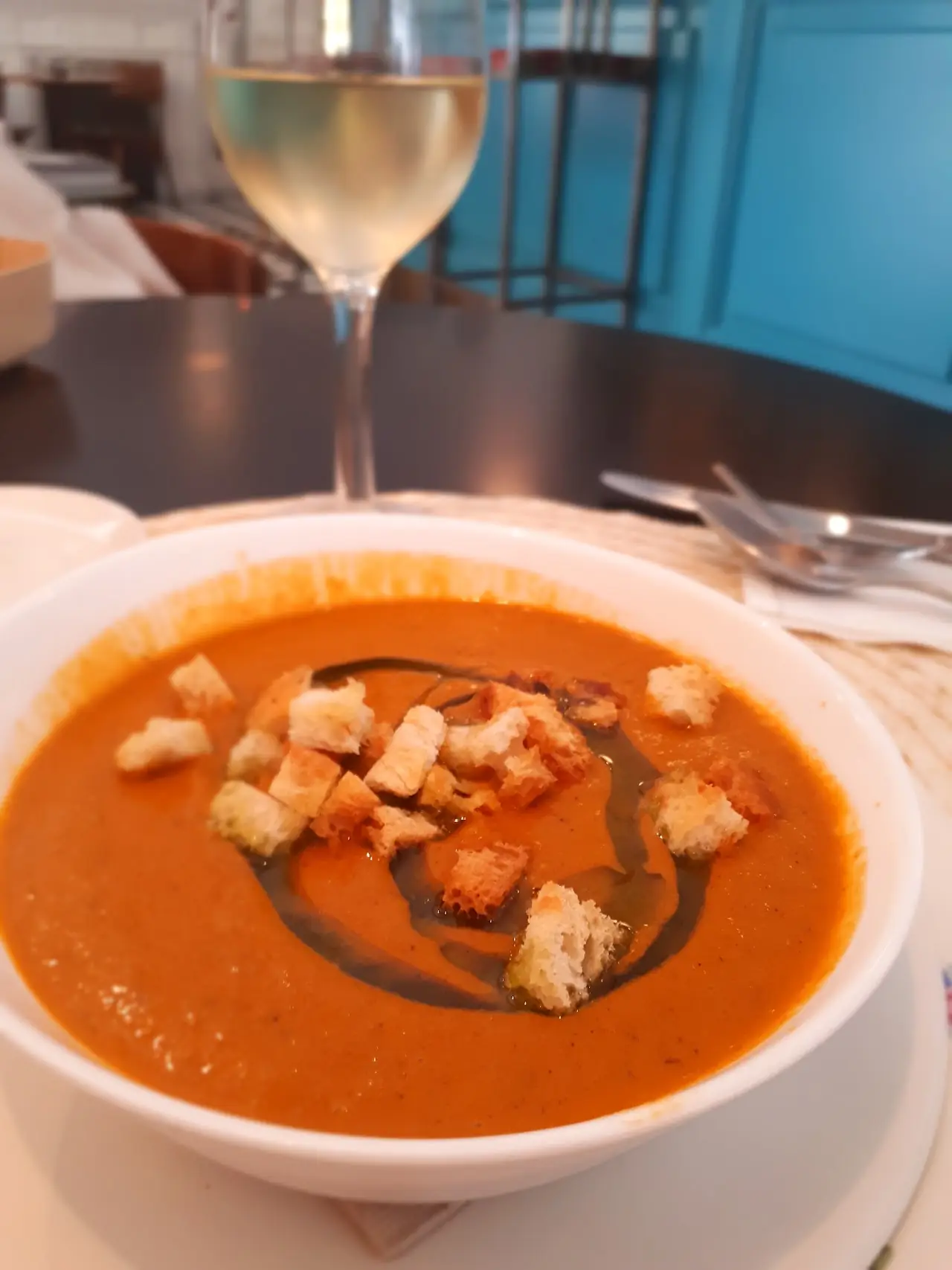 Bowl of tomato soup drizzled with a dark reduction and topped with croutons