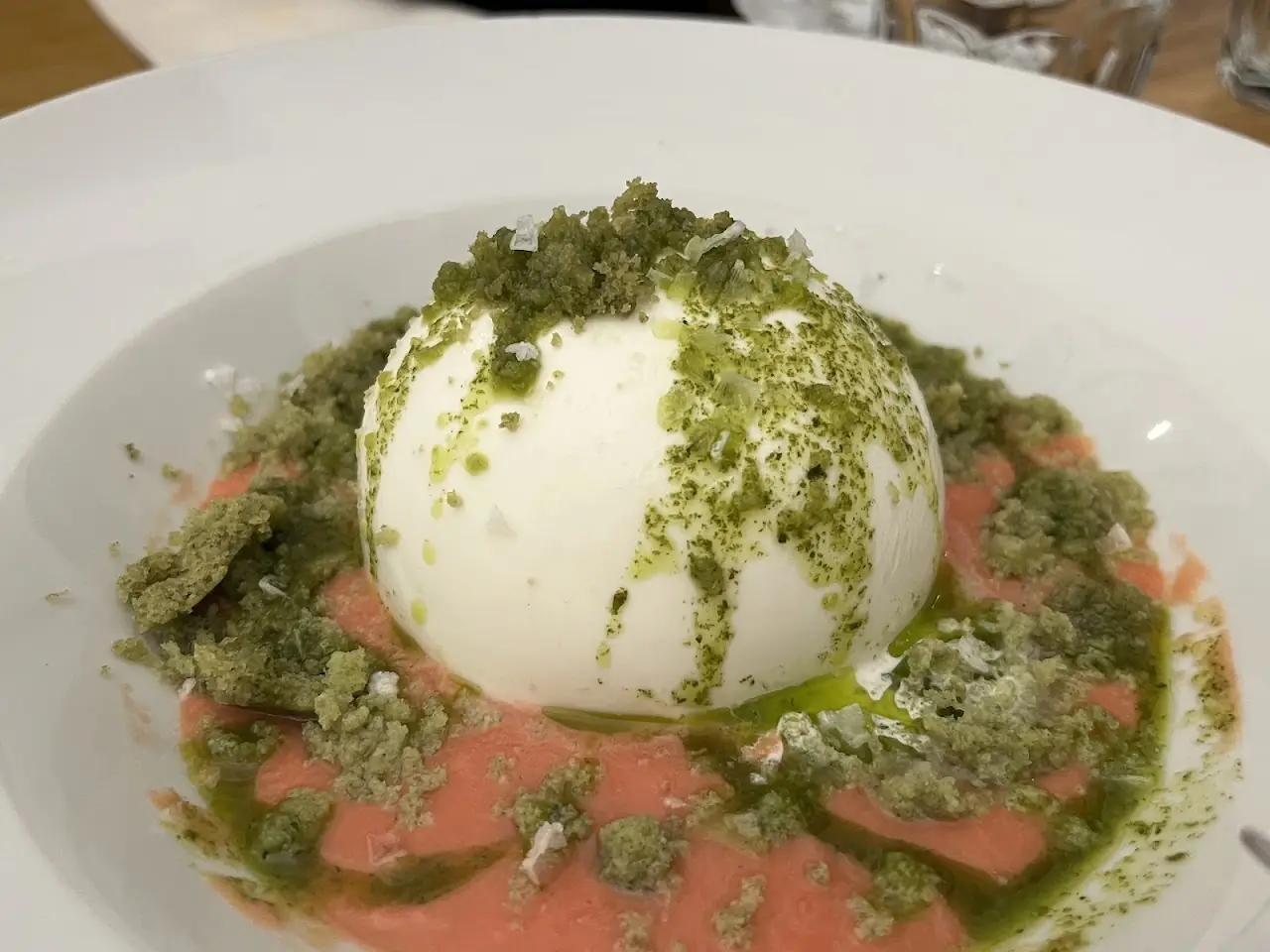 Whole burrata dusted with herb crumble over a smear of tomato sauce