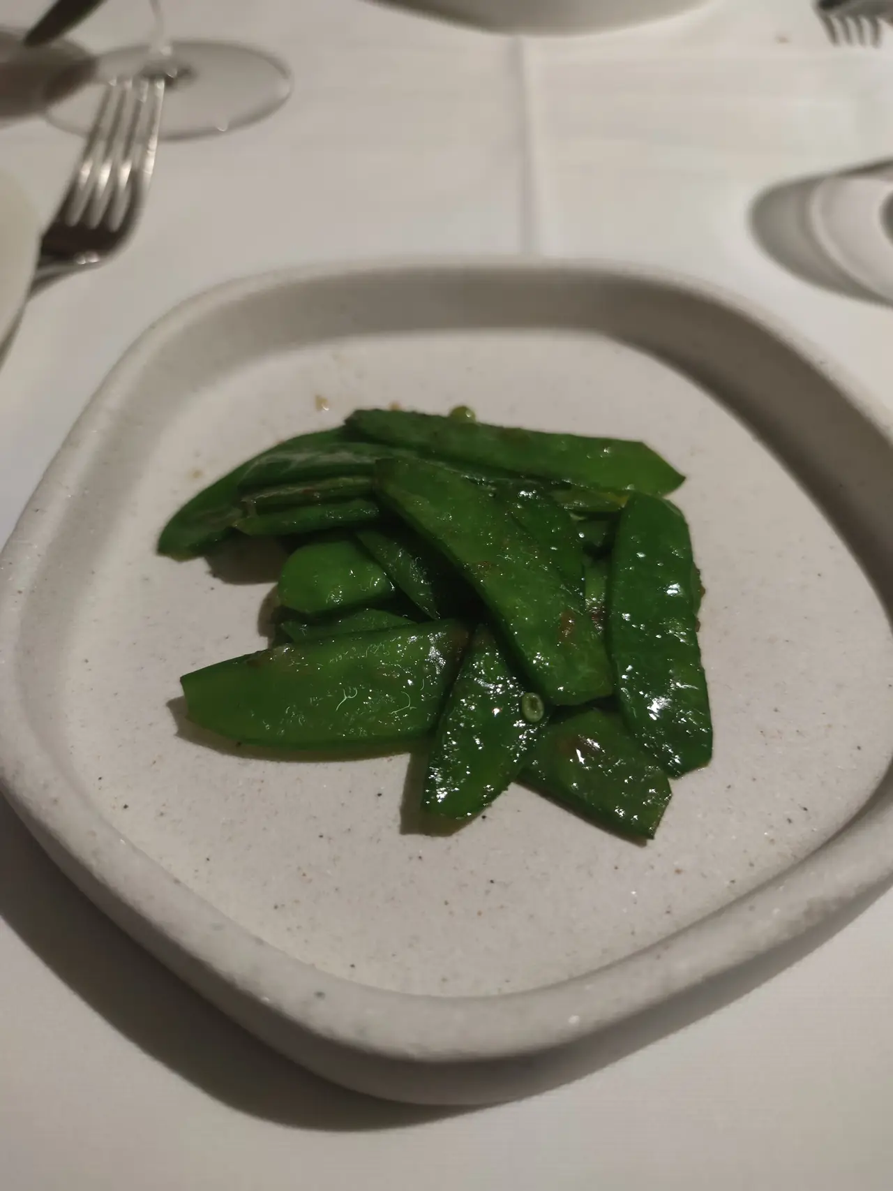 Sauteed snap peas glazed and plated on a ceramic dish