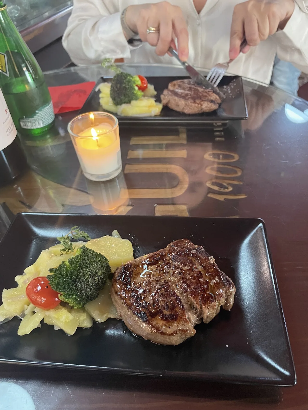 A seared steak with mashed potatoes and broccoli on a black plate