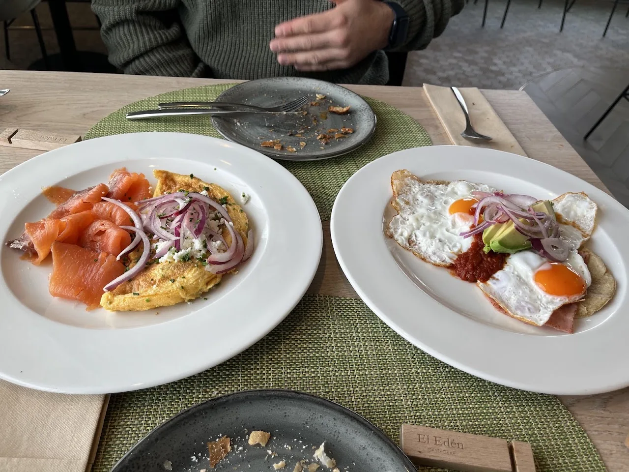 Two open-faced toasts topped with smoked salmon, fried eggs, and red onion