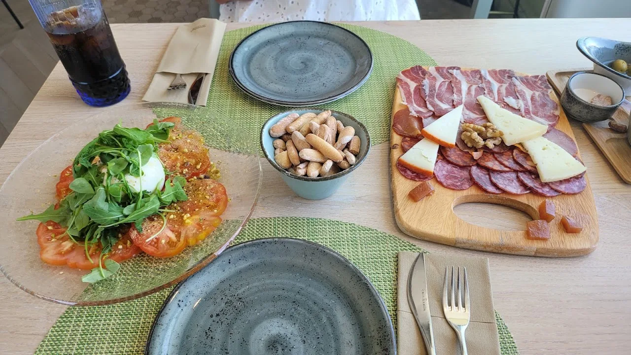 A tomato and arugula tostada beside a charcuterie and cheese board