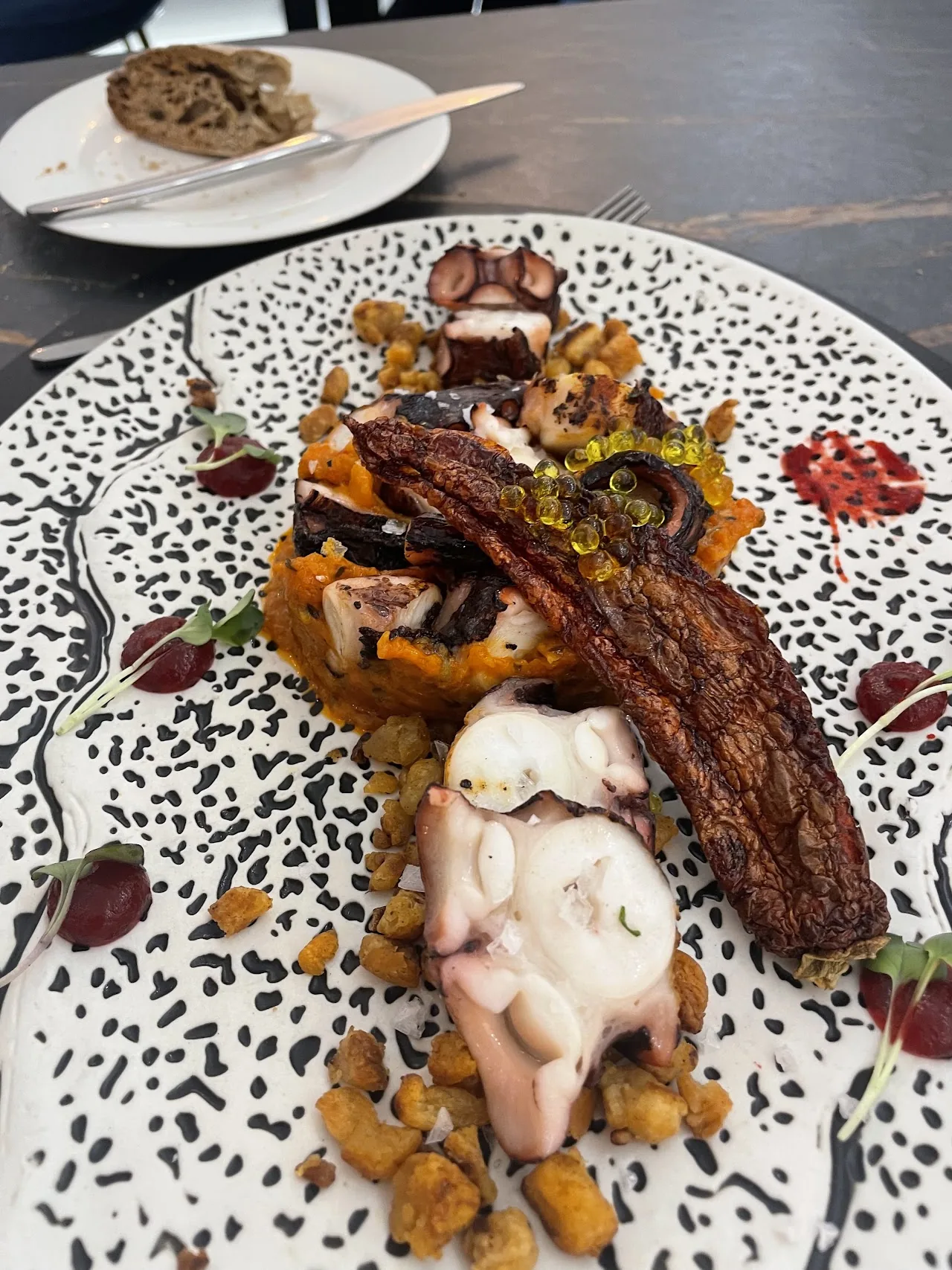 A plate of grilled ribs and octopus with roasted vegetables