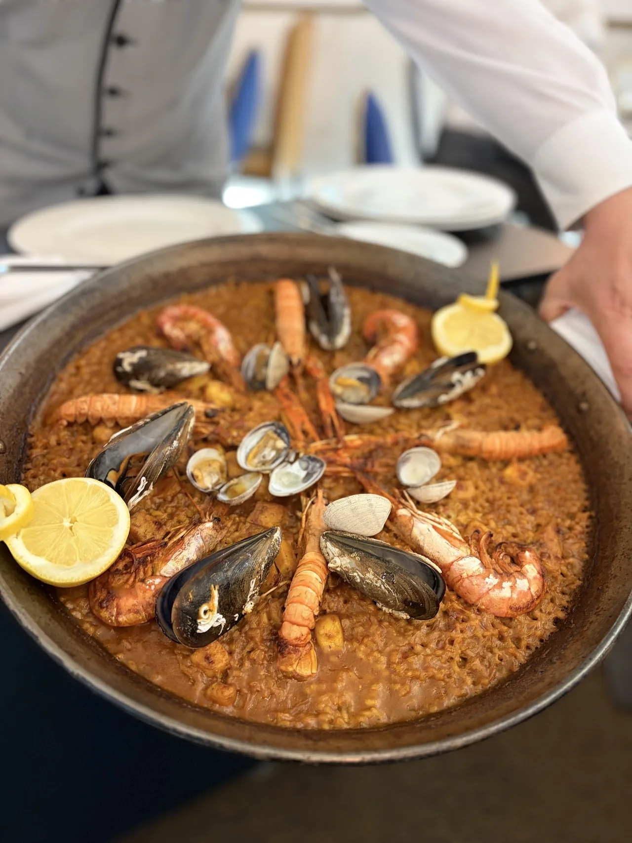 A paella pan filled with rice, shrimp, and mussels