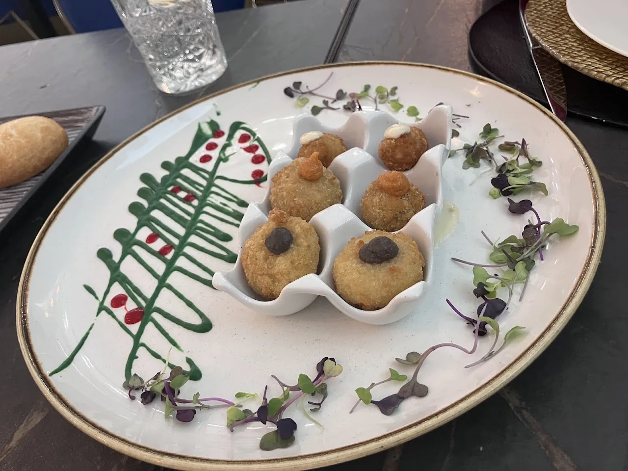 An oval plate of fried croquettes garnished with herbs