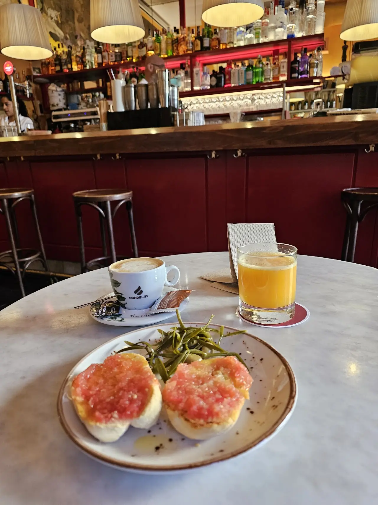 Toasted bread with grated tomato, served alongside a coffee and a glass of orange juice.