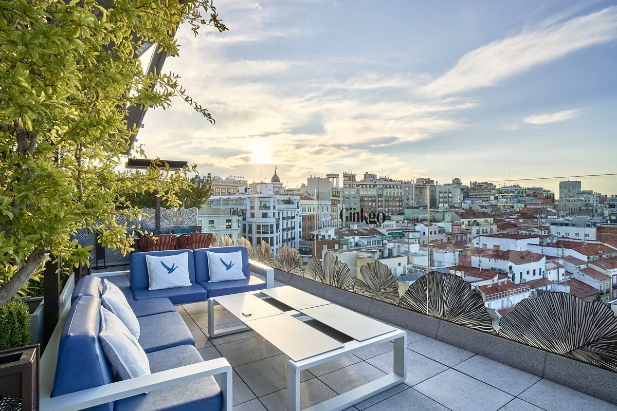 Blue sofas and a low table on a rooftop terrace looking out over Madrid rooftops