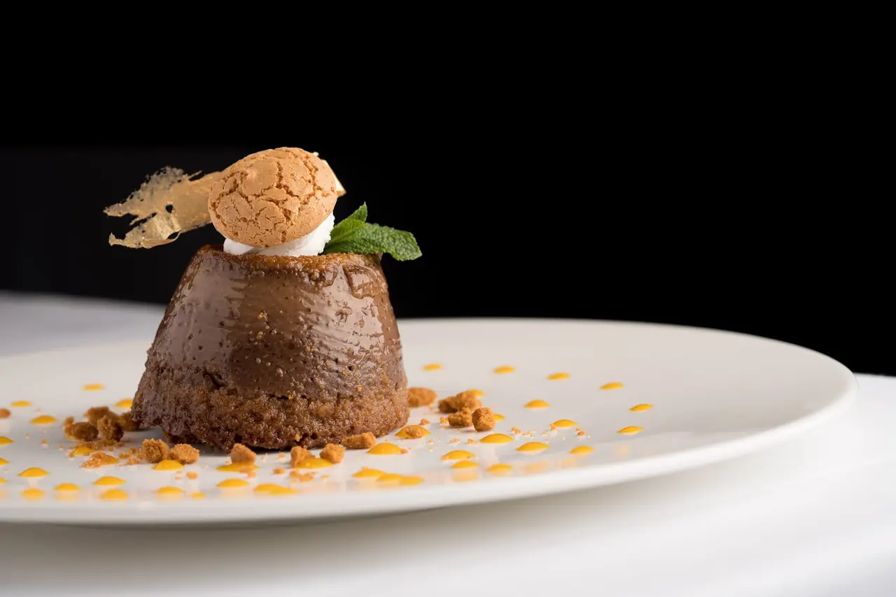 Chocolate budino dessert with amaretti cookie, gold leaf and caramel dots