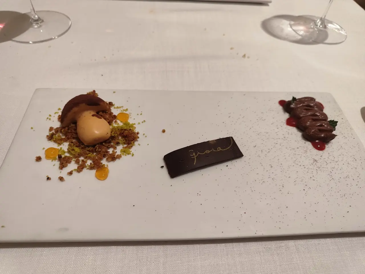 Dessert tasting plate with a chocolate quenelle, piped mousse and a branded chocolate plaque