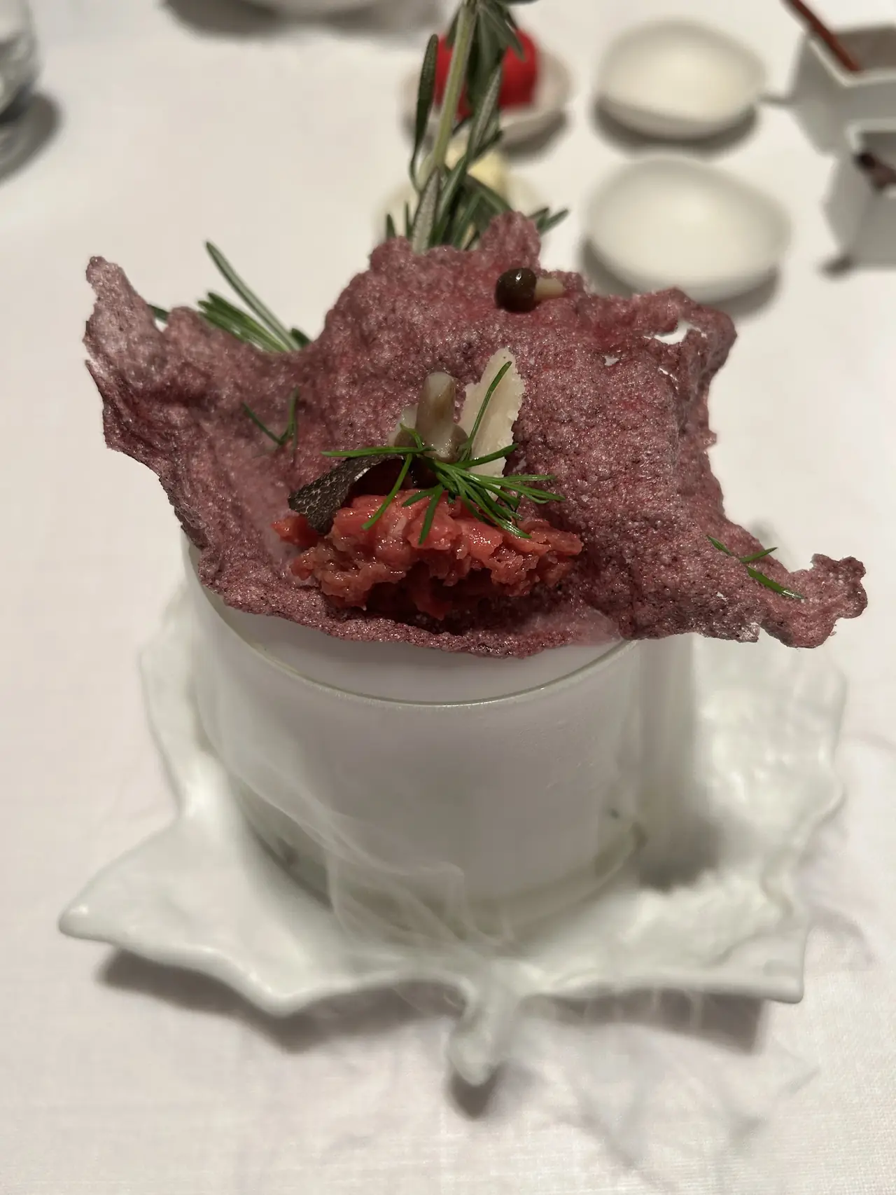 Beet crisp filled with tartare, herbs and shaved cheese on a leaf-shaped dish