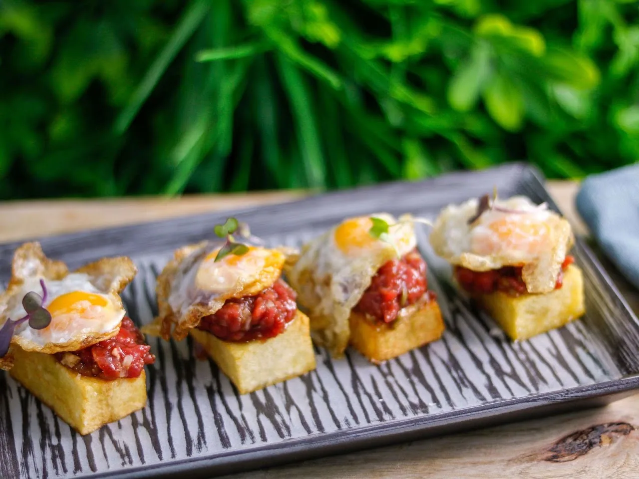 Toasted bread bites topped with fried egg and diced tomato