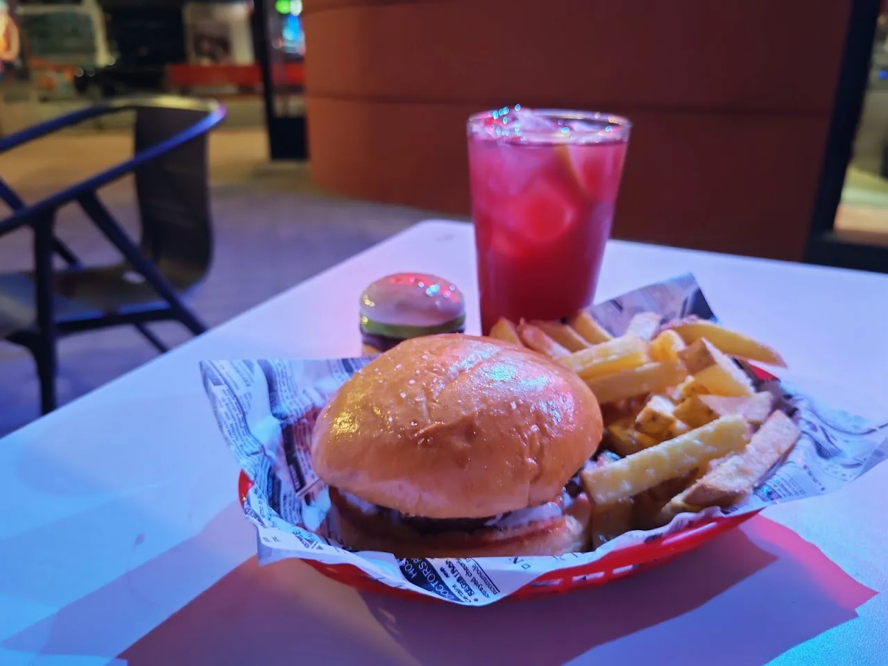 A burger with french fries in a paper-lined basket, with a drink