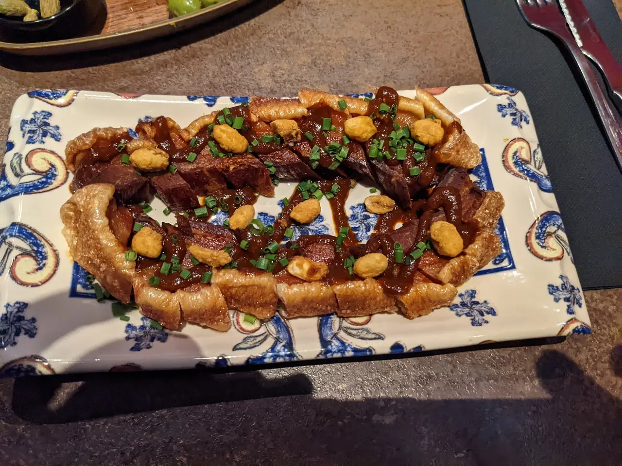 Sliced glazed ribs topped with peanuts and chives on patterned platter