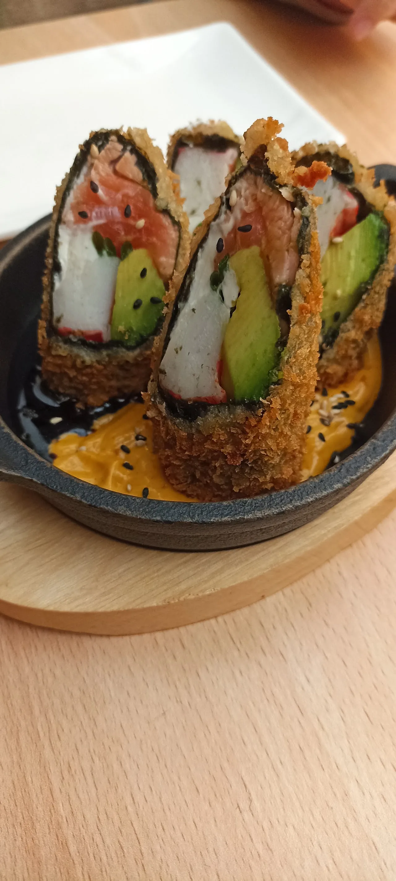 Sushi rolls with avocado and a crispy topping on a wooden board