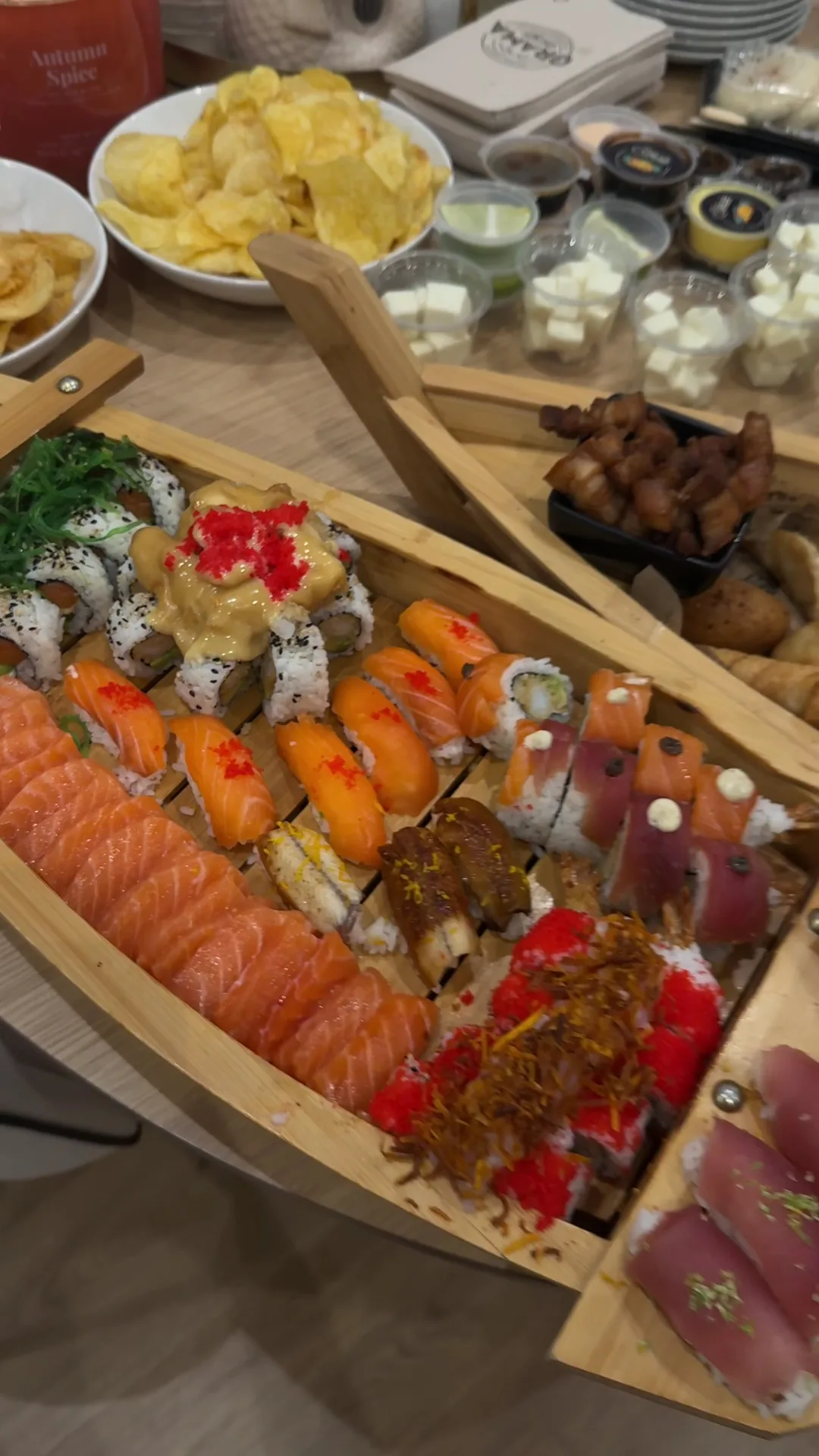 A wooden board with sashimi, sushi, and seafood tapas