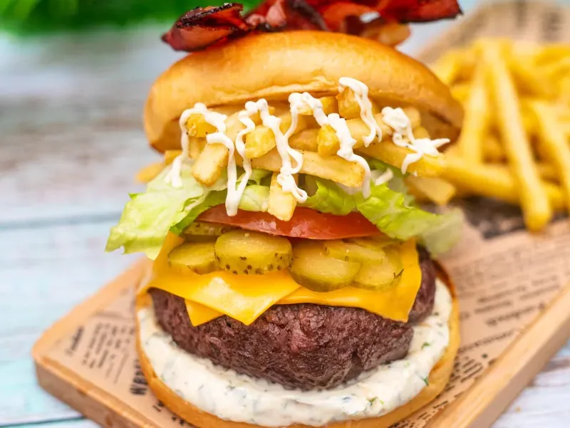 A cheeseburger with lettuce, tomato, and pickles served with fries
