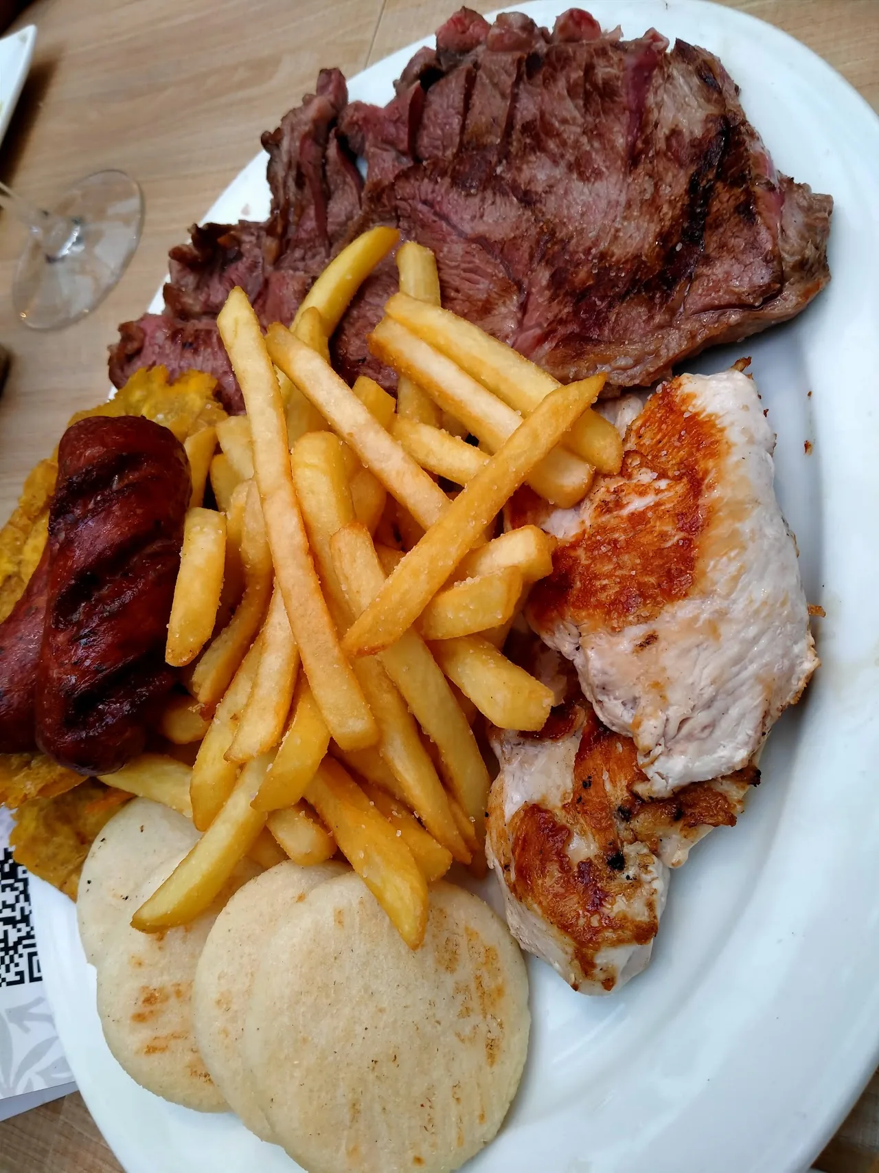 A plate of grilled meat, fries, chicken, and fried plantains
