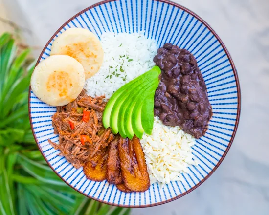 A colorful bowl with rice, black beans, avocado, shredded meat, and boiled eggs