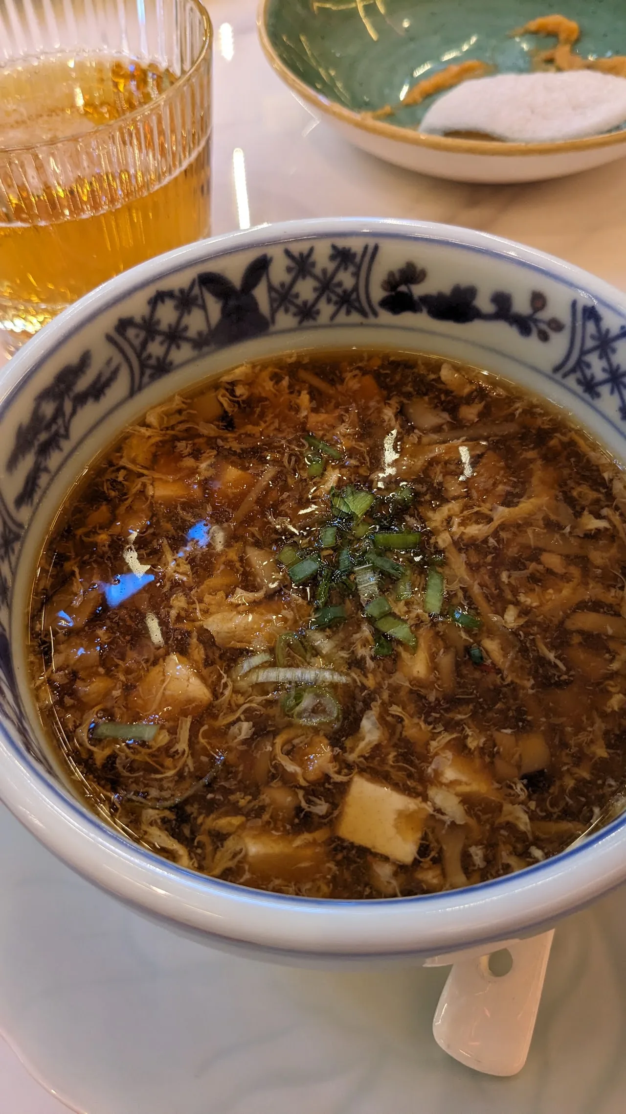 A bowl of broth soup with noodles and tofu