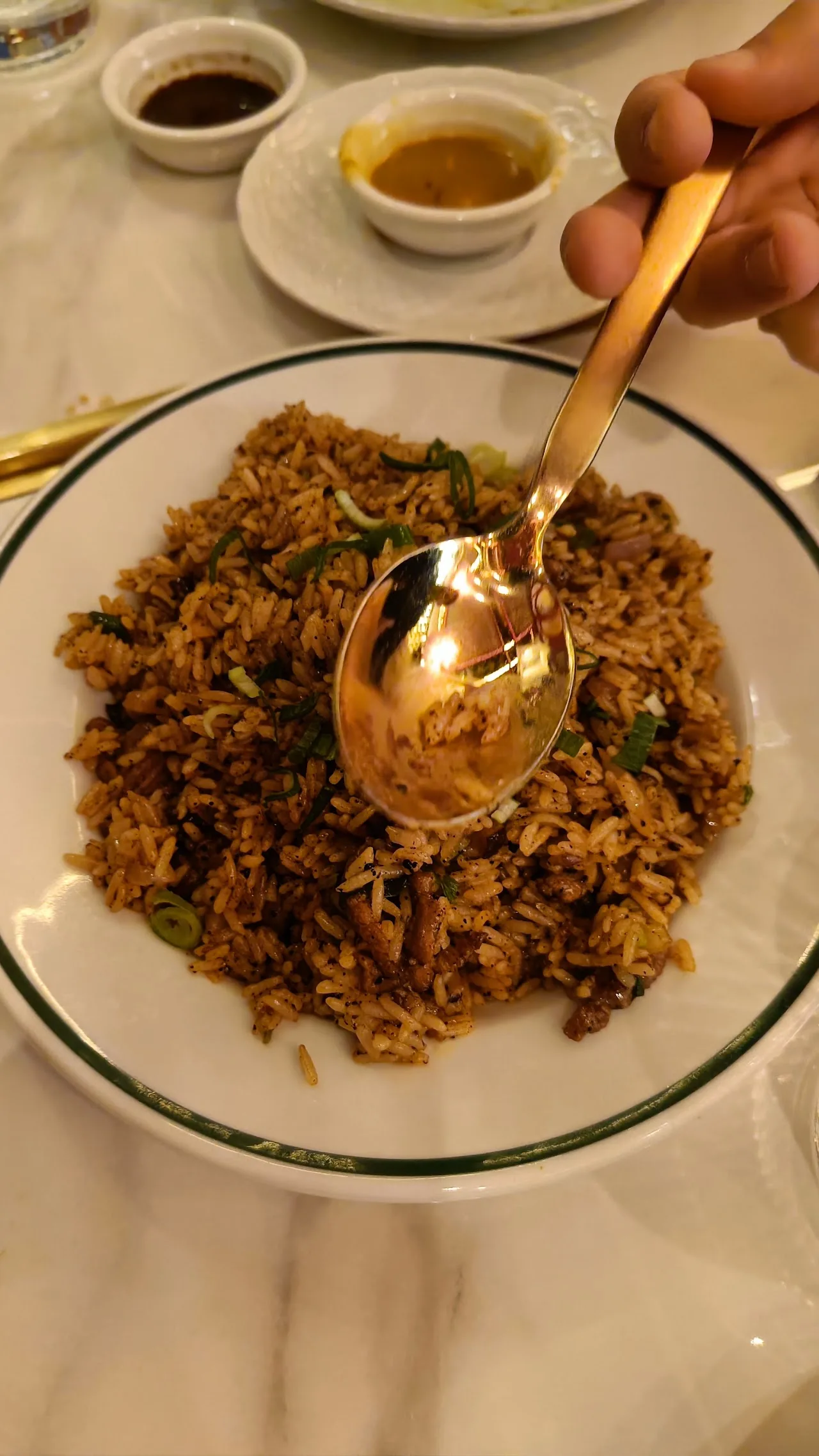 A bowl of fried rice with a golden spoon